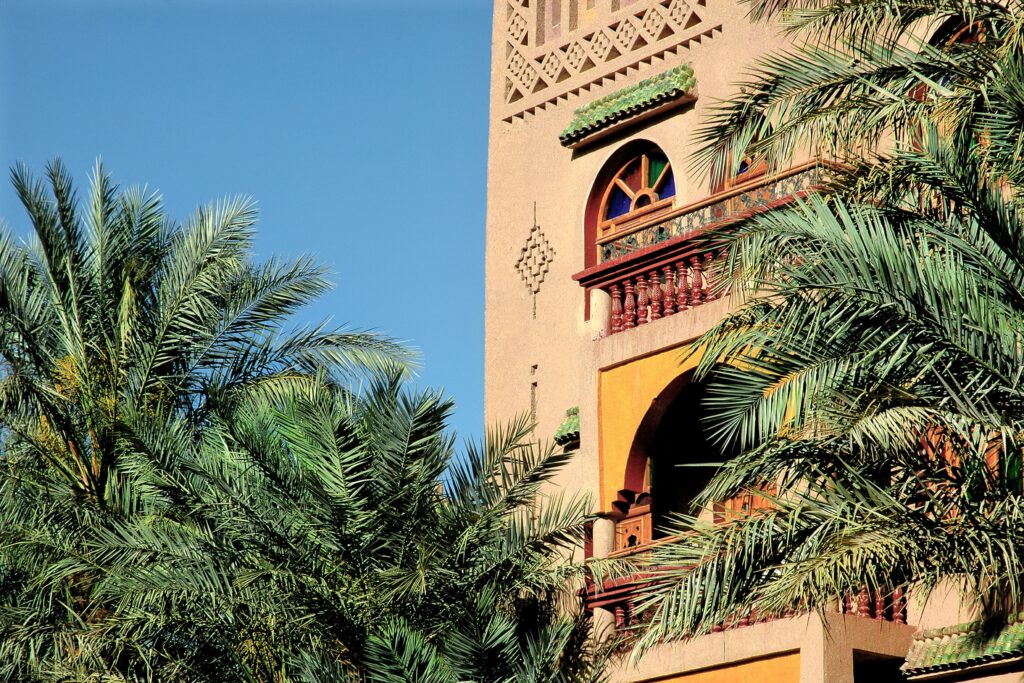 Elegant Moroccan architecture with palm trees under a clear blue sky in Zagora, Morocco.